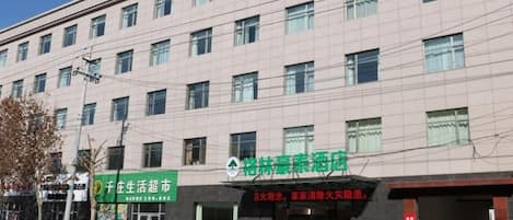 A multi-story building with a flat facade, several windows, and a green signboard.