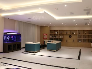 Una sala de estar moderna con una televisión de pantalla plana, dos sofás, una mesa de centro y una estantería decorativa con varios objetos.