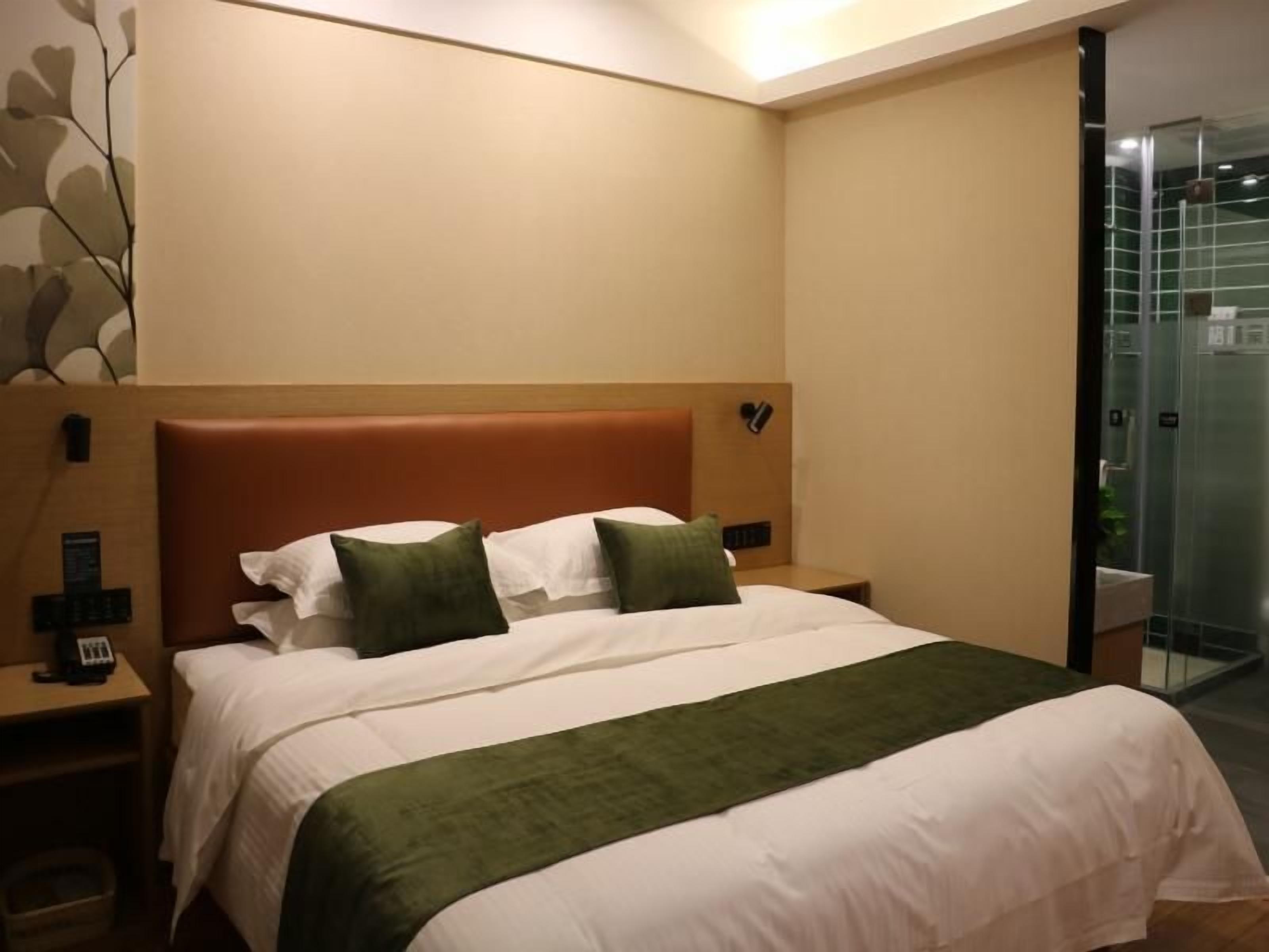 A hotel room with a bed, bedside tables, and a shower area.