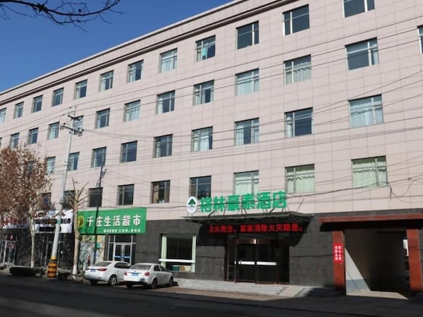 Un edificio de varios pisos con fachada plana, varias ventanas y un letrero verde.