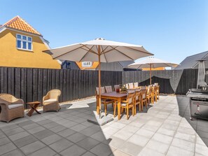 A patio with a table and chairs, outdoor umbrellas, and a grill. - "Judyta" - 500m from the sea by Interhome (Skagen)