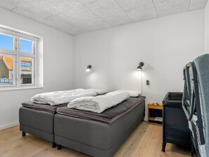 Ein Schlafzimmer mit einem Bett, Nachttischlampen, einem Sessel und einem Fenster.