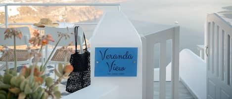 Un balcón con vistas, un cartel que dice 'Veranda View', una mesa con sillas y un sombrero.