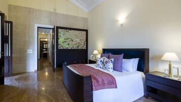 A hotel room with a large bed, a nightstand, a wall-mounted artwork, and a door leading to another room.