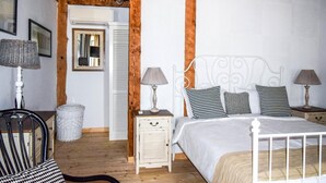 Quarto com cama, duas mesas de cabeceira, uma cadeira, luminária e espelho.