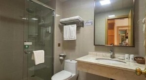 Un baño con ducha de mampara de vidrio, inodoro y lavabo con espejo.