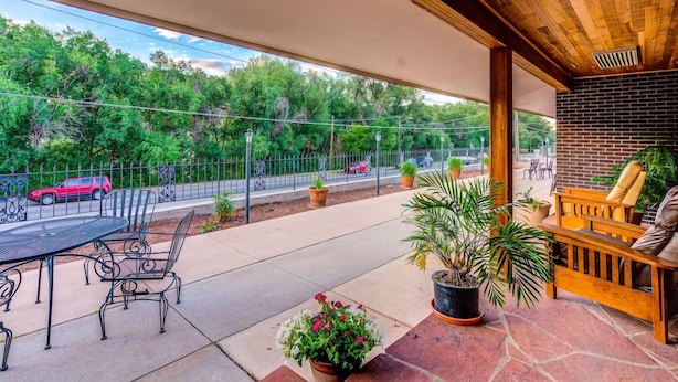 A covered patio with outdoor seating, a table, and chairs. - Innhale Cannabis Friendly B&B - Adults Only (Manitou Springs)