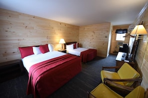 A hotel room with two beds, a desk, a chair, and a lamp. - The Welcome Inn (Mackinaw City)