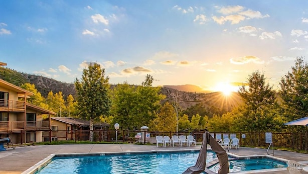 A swimming pool with a sunken chair, surrounded by lounge chairs and a view of a mountain range. - Willows, a Destination by Hyatt Residence (Snowmass Village)
