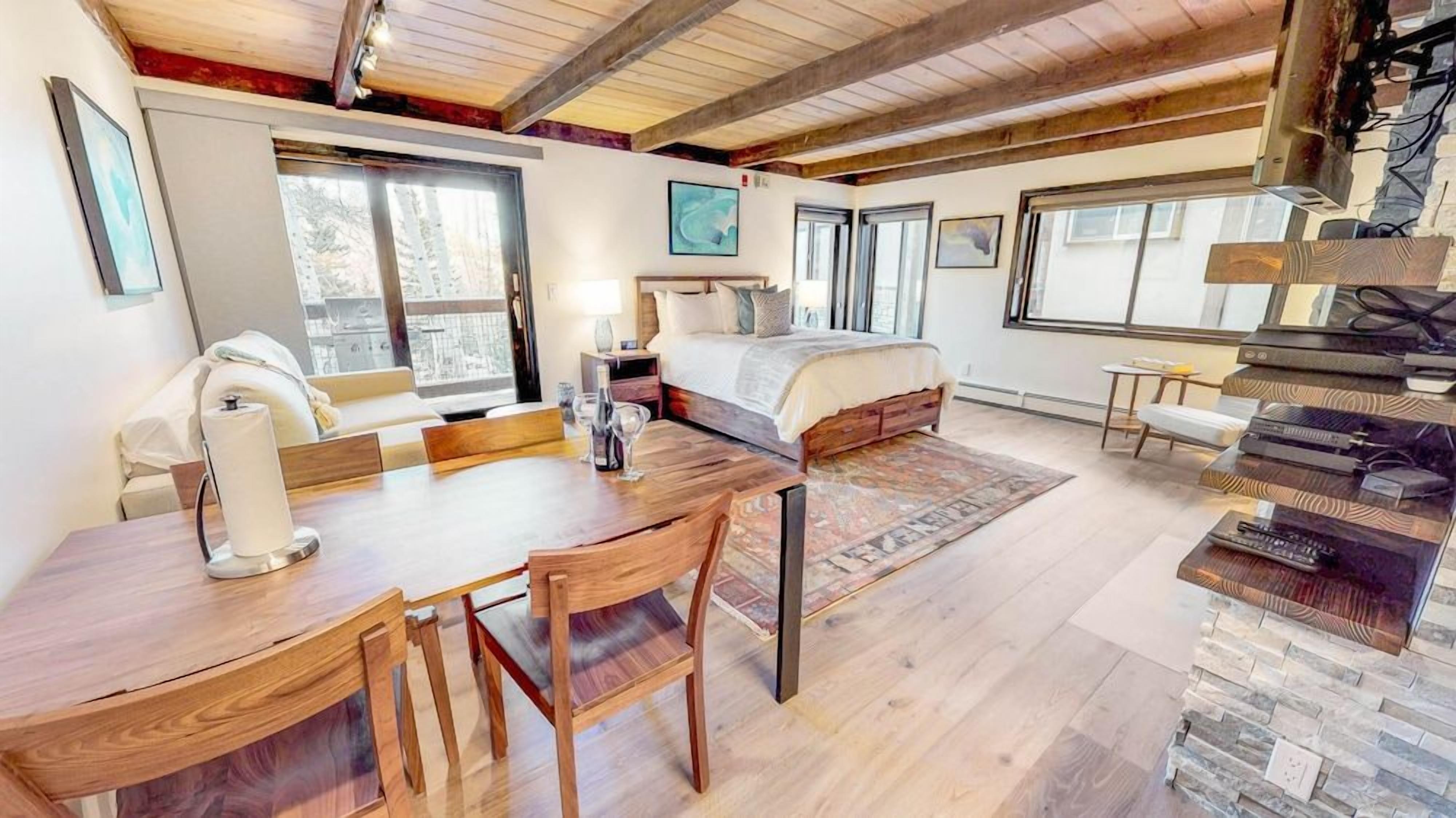 A spacious bedroom with a large bed, a wooden dining table, and a cozy seating area.