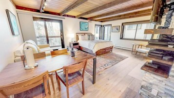 A spacious bedroom with a large bed, a wooden dining table, and a cozy seating area.