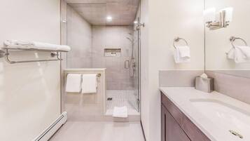 A modern bathroom with a glass-enclosed shower, a vanity with a mirror, and a towel rack.
