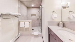 Une salle de bain moderne avec une douche à parois de verre, un meuble-lavabo avec un miroir et un porte-serviettes.