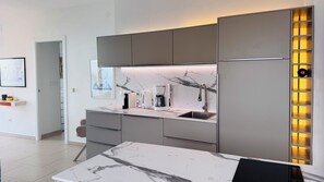 A modern kitchen with a marble countertop, built-in appliances, and a wine rack. - Refugio Cerro Gordo Studio 1: A Dream Castle (La Herradura)