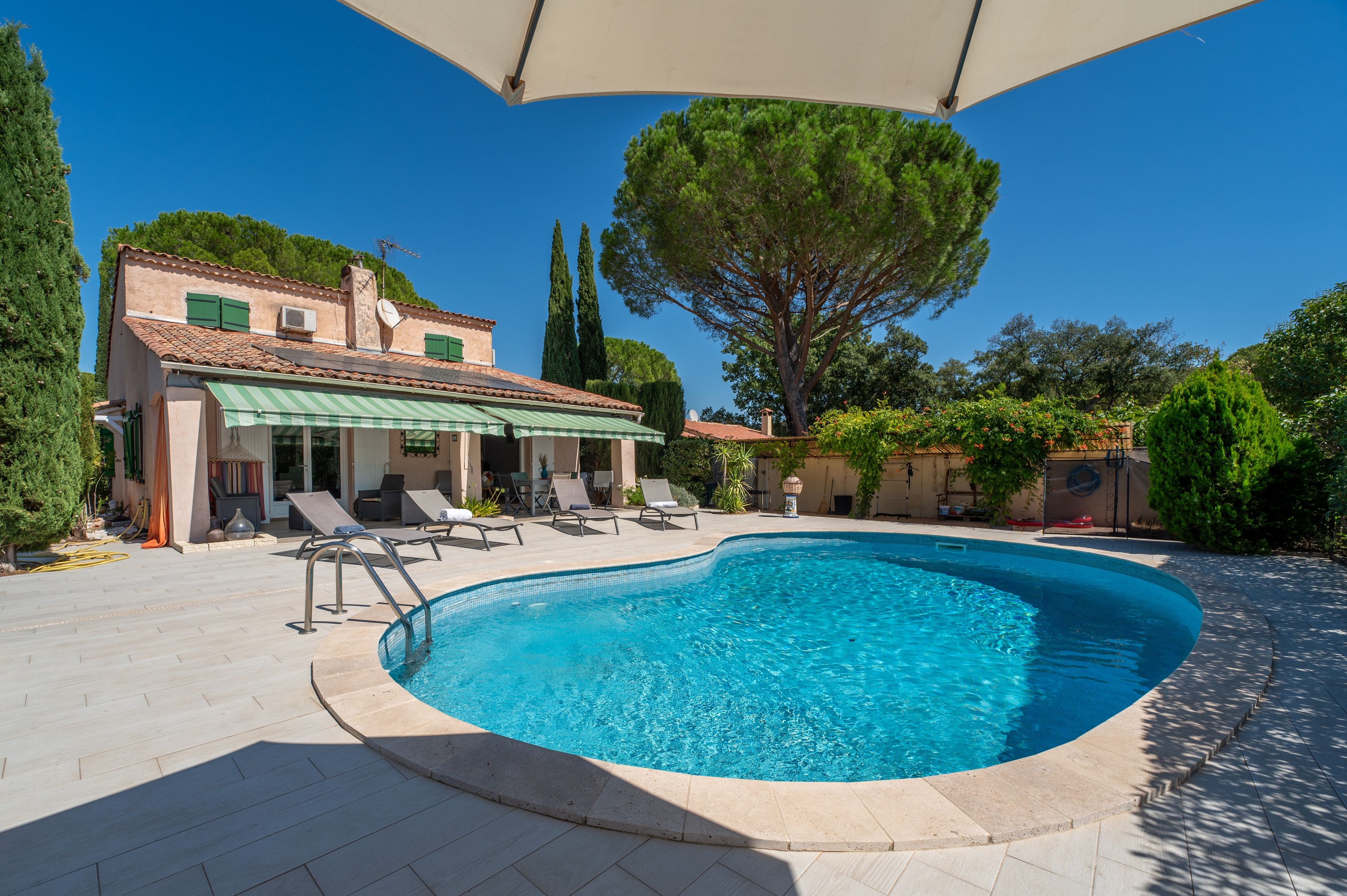A swimming pool with lounge chairs and a covered patio area.