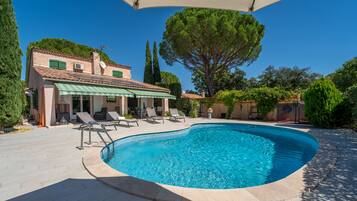 A swimming pool with lounge chairs and a covered patio area.