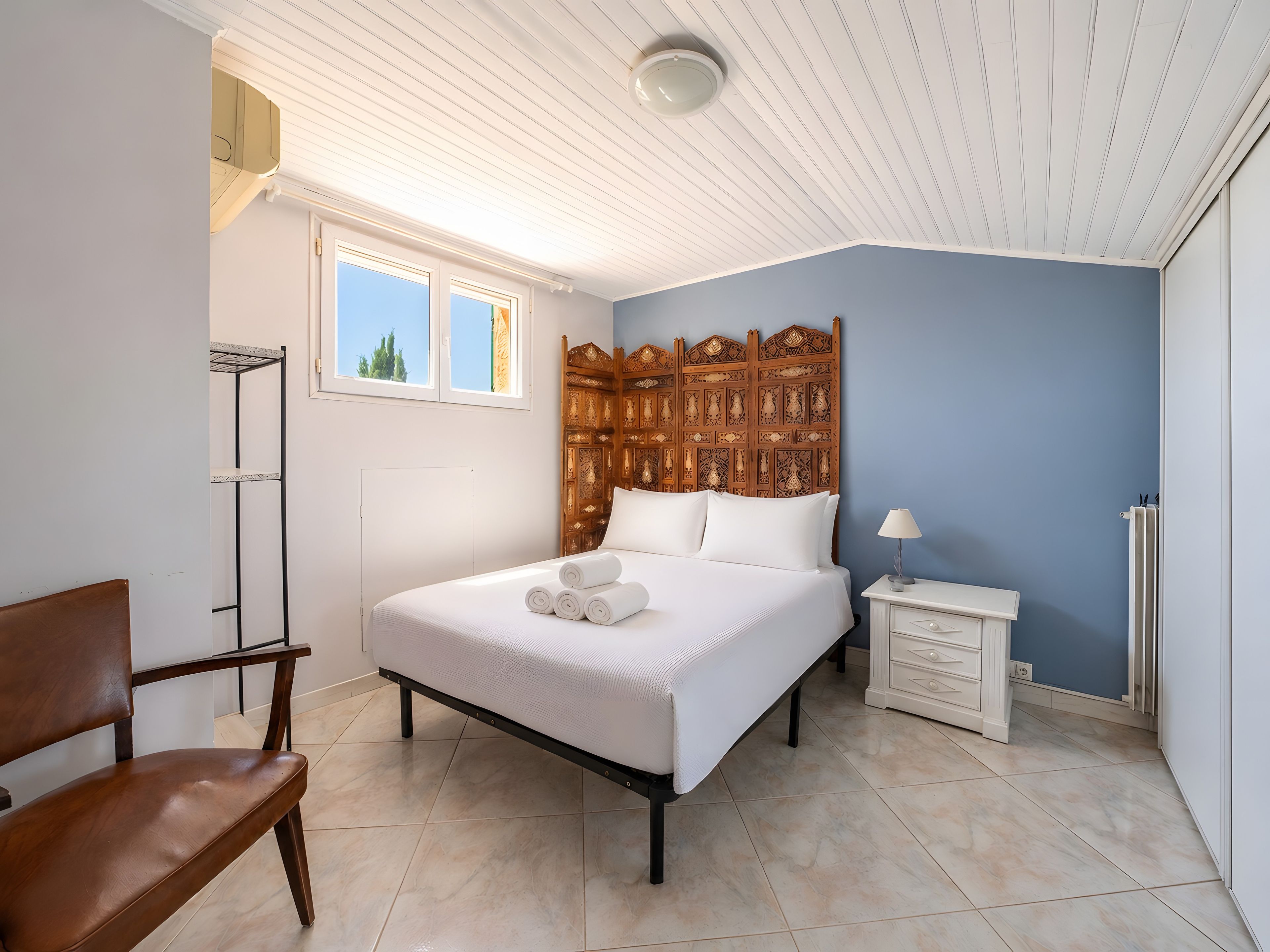 Ein Schlafzimmer mit Bett, Nachttisch, Stuhl, Heizkörper und Fenster.