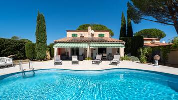 A swimming pool with lounge chairs and a covered patio area.