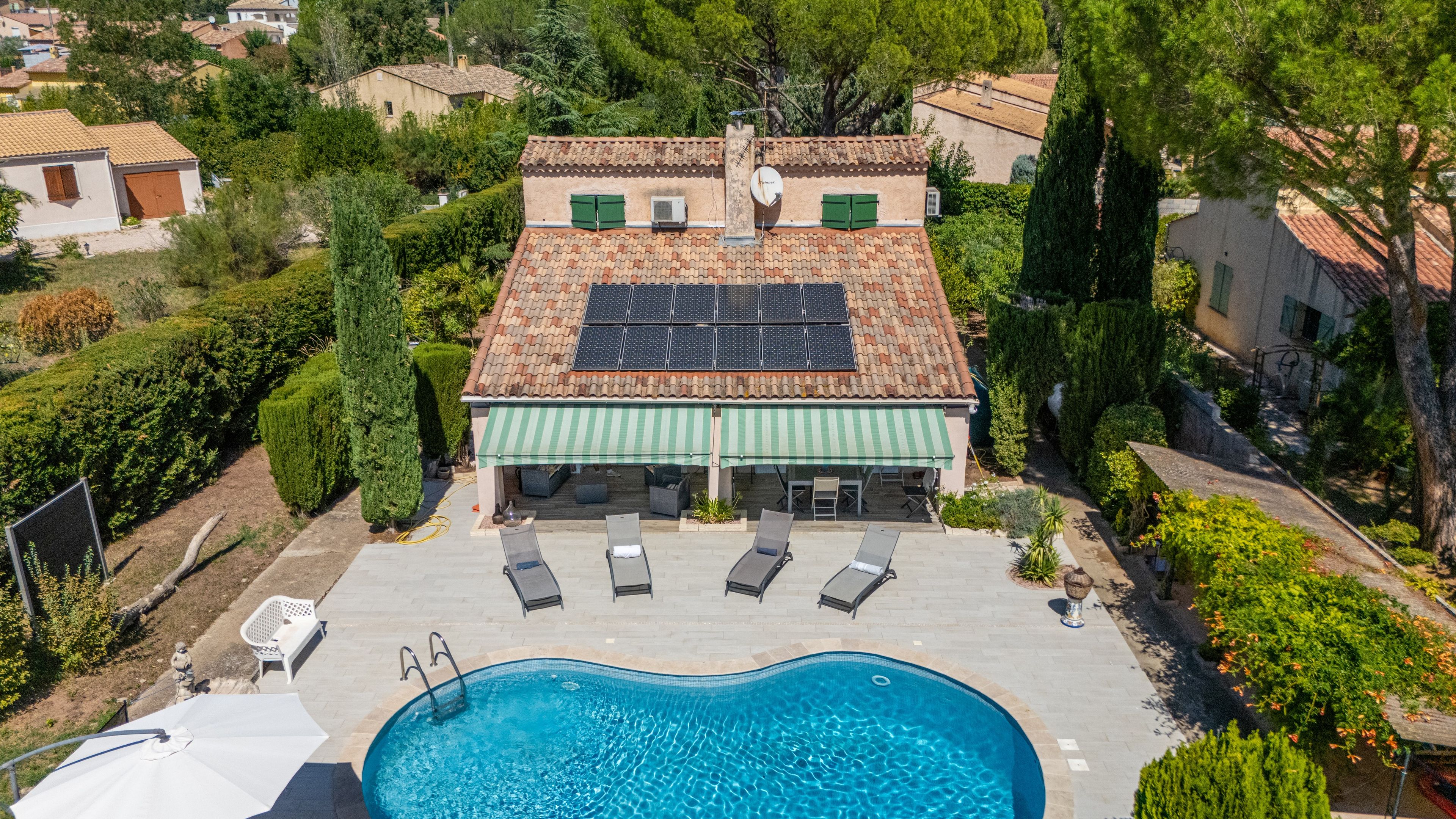 Una propiedad residencial con piscina, paneles solares y un patio cubierto.
