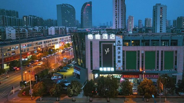 A hotel with a prominent sign, surrounded by a cityscape with other buildings and a busy street. - GYA Jurong Yinglun International Hotel (Zhenjiang)