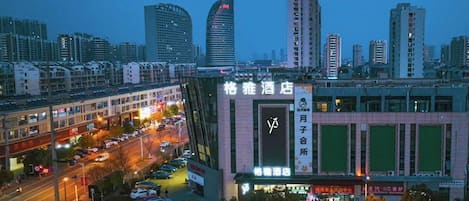 A hotel with a prominent sign, surrounded by a busy urban street and tall buildings.