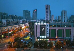 A hotel with a prominent sign, surrounded by a busy urban street and tall buildings.