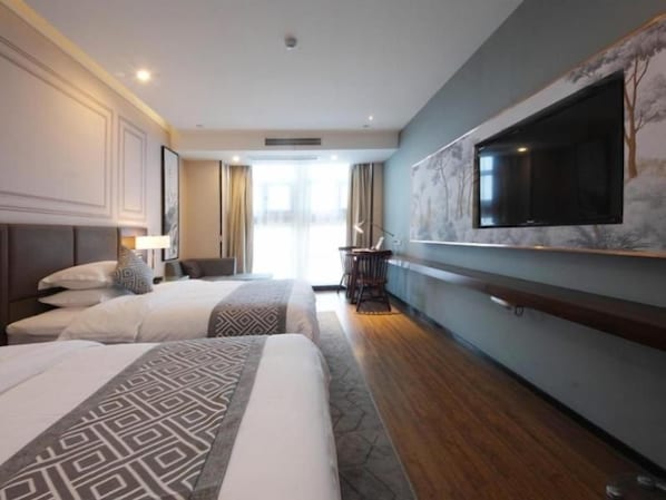 Une chambre d’hôtel avec deux lits, un téléviseur à écran plat fixé au mur et une grande fenêtre.
