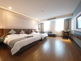 Una habitación de hotel con dos camas, un escritorio y un ventanal grande.