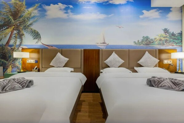 A hotel room with two beds, a mural of a beach scene, and a nightstand with a lamp.