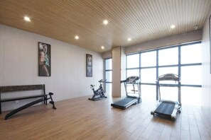 Ein Fitnessraum mit Holzboden, einer Bank, einem Ergometer und Laufbändern.