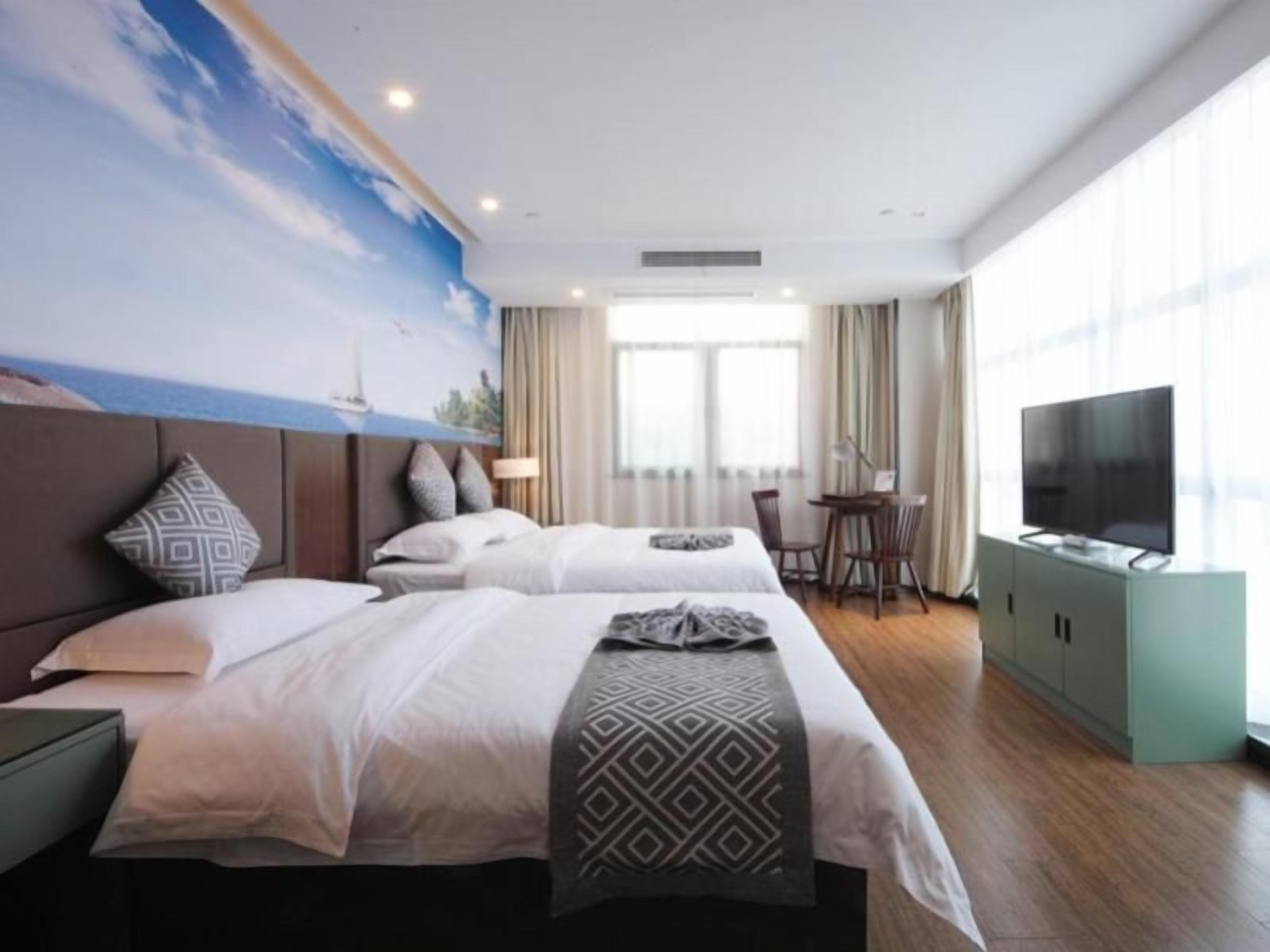 Una habitación de hotel con dos camas, televisión, escritorio y un ventanal grande.