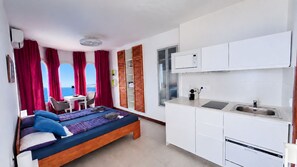 A bedroom with a bed, a desk, and a view of the sea. - Studio 2, Refugio Cerro Gordo (La Herradura)