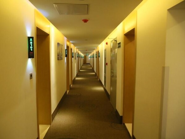 Corredor de hotel com portas de ambos os lados, cada uma delas identificada com um número.