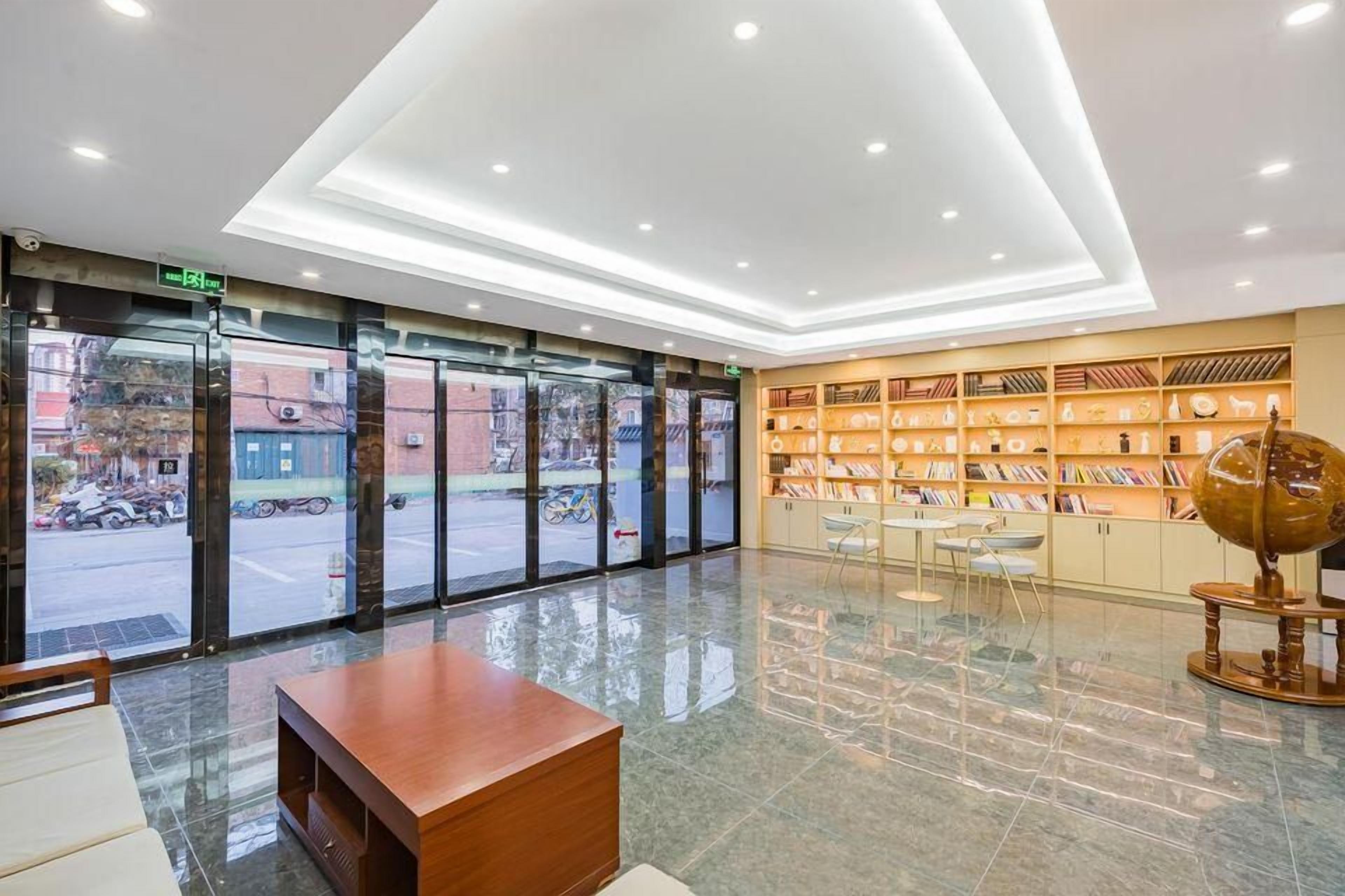 A hotel lobby with a reception desk, a seating area, a bookshelf with books, and a large globe.