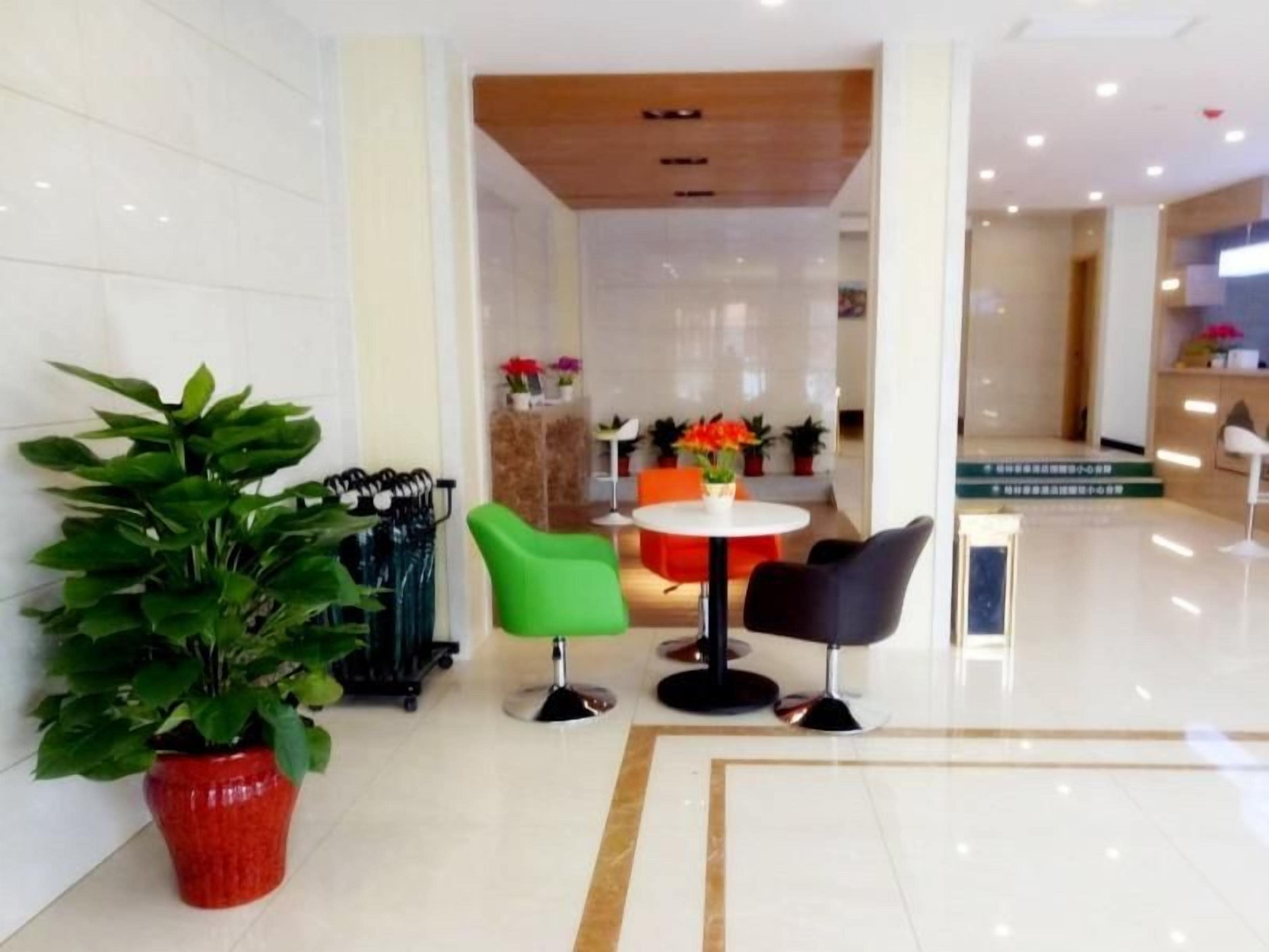 A hotel lobby with a reception desk, seating area, and potted plants.