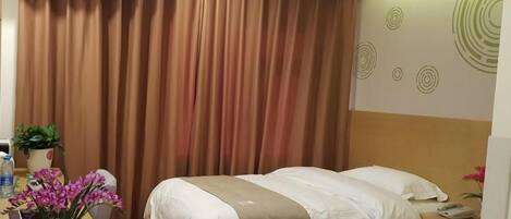 A hotel room with two beds, a wooden nightstand with a potted plant, and a wall-mounted air conditioner.