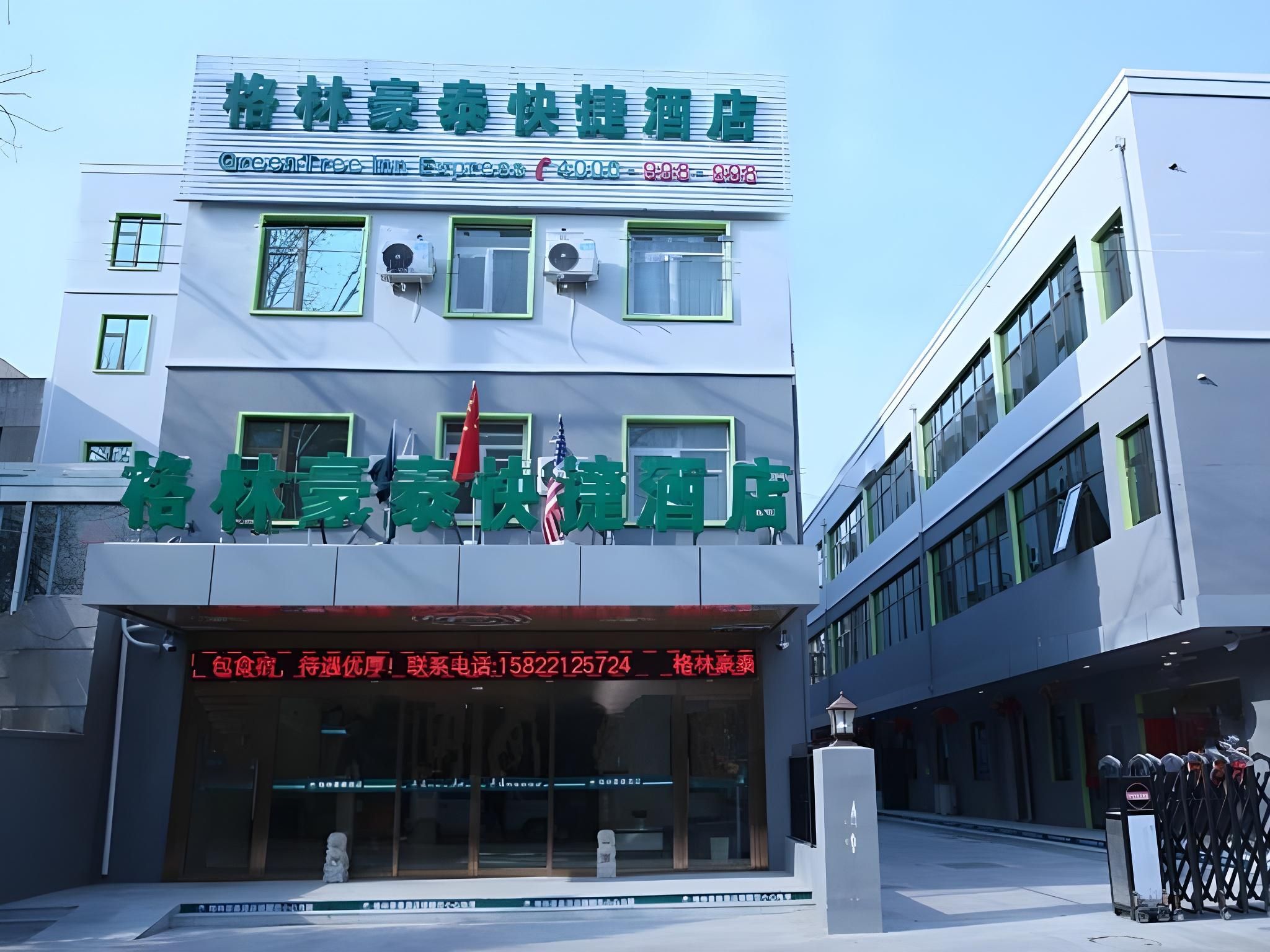 A hotel with a modern facade, large windows, and a prominent sign with contact information.