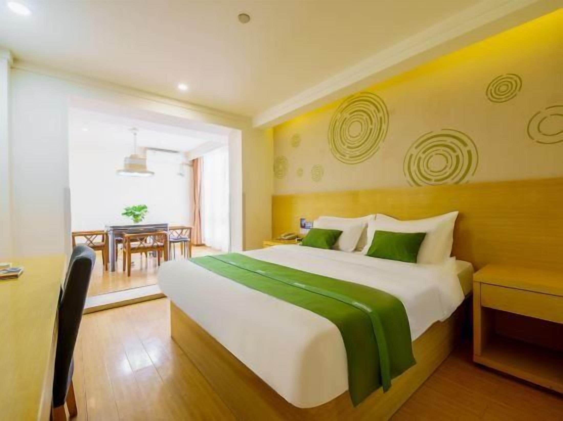 A hotel room with a bed, bedside table, and a desk with a chair.