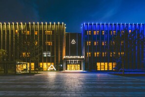 Hotel com fachada moderna, entrada imponente e exterior bem iluminado.