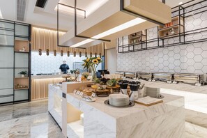 Cozinha moderna com bancada de mármore, um chef preparando comida e parede com padrão hexagonal.