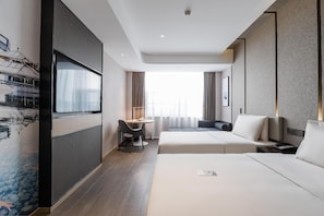 Quarto de hotel com cama, escrivaninha, cadeira, sofá e uma janela grande.