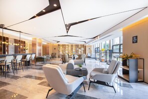 A modern hotel lobby with seating areas, a bar, and a bookshelf. - Atour Hotel (Kunming)