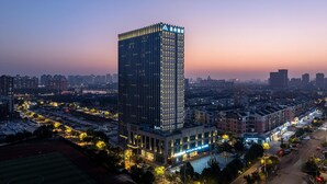 Un hôtel de grande hauteur au design moderne, entouré d’un paysage urbain au crépuscule.
