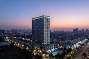 Um hotel moderno e imponente, rodeado por um horizonte urbano ao crepúsculo.