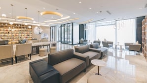 Un hall d’hôtel moderne avec un espace salon, une bibliothèque et un comptoir d’accueil.