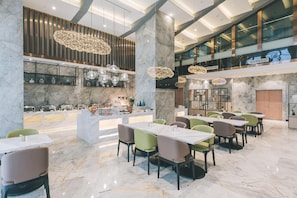 Uma ampla sala de jantar com piso de mármore, luminárias modernas e diversas opções de assentos.