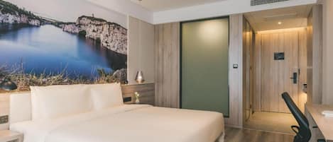 Une chambre d’hôtel moderne, dotée d’un grand lit, d’un bureau et offrant une vue sur un paysage naturel.