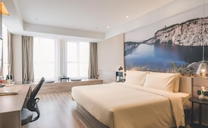 Quarto de hotel com uma cama grande, uma escrivaninha e vista para falésias e água.