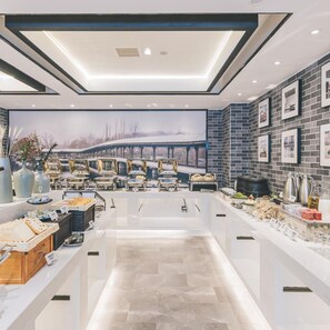 A modern kitchen with a central island, equipped with various appliances and a large window overlooking a snowy landscape. - Atour Hotel (Jiaxing)