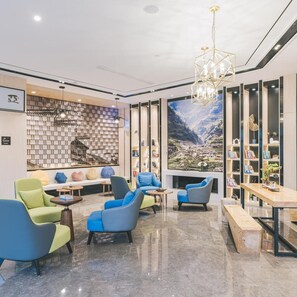 A modern lounge area with seating, a fireplace, and a large bookshelf. - Atour Hotel (Jiaxing)